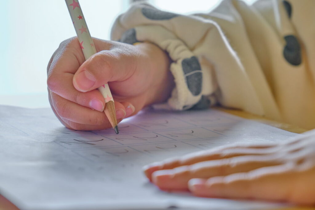 えんぴつで文字を書いている子ども